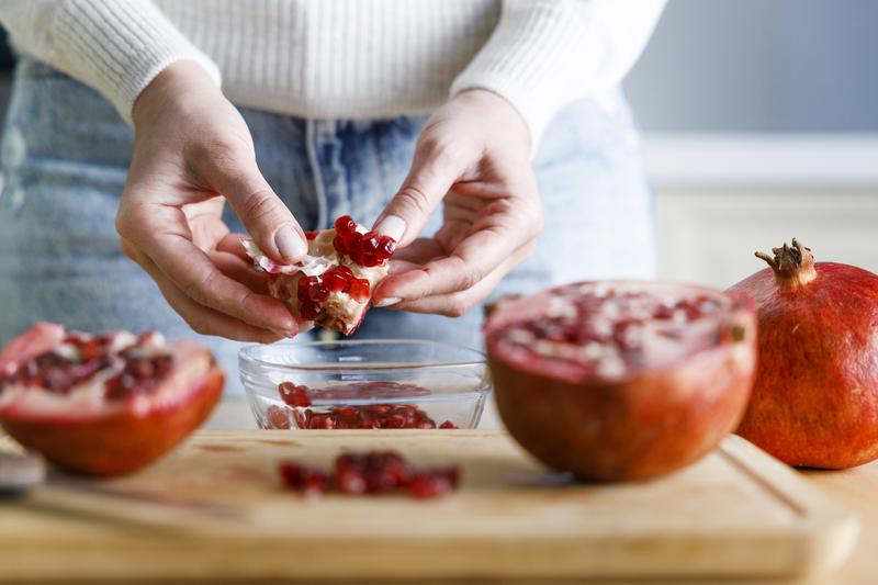 Granatapfel wird über einer Glasschüssel entkernt