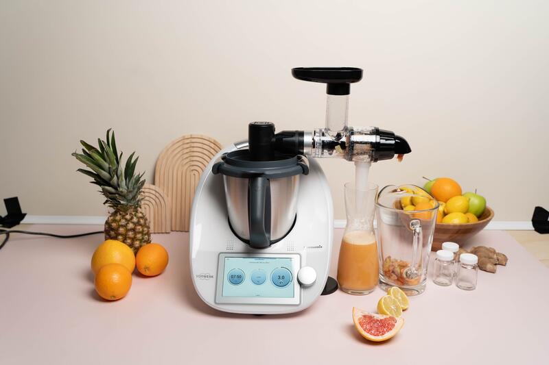 Thermomix® mit WunderCentix® Aufsatz, im Behälter ist Orangensaft, daneben liegt Obst