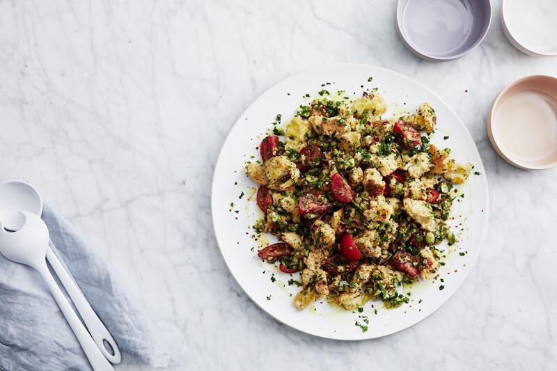 Brotsalat mit Tomaten von oben fotografiert auf einem weißen Teller und hellem Untergrund