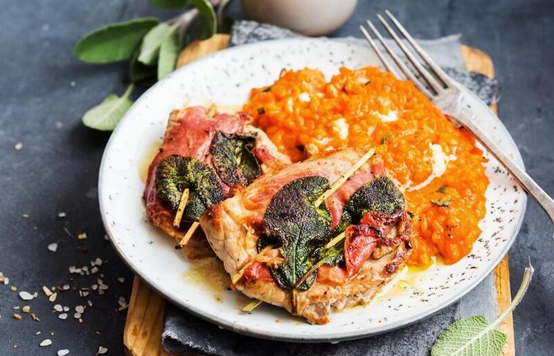 Fleisch und Risotto auf einem weißen Teller mit Salbei garniert