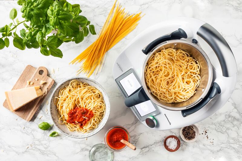 Spaghetti im Mixtopf des Thermomix® von oben fotografiert, daneben ein Teller mit Spaghetti