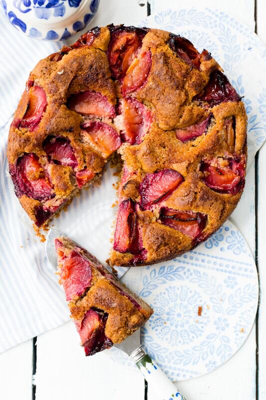 Ganzer glutenfreier Pflaumenkuchen mit einem geschnittenen Stück