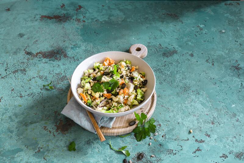 Große weiße Schüssel mit Brokkoli-Blumenkohl-Salat mit Karotten und Kernen