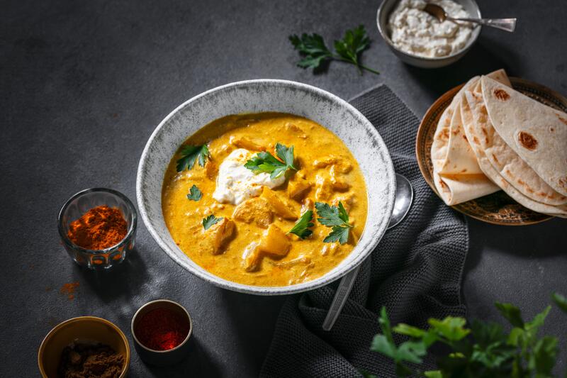 Tiefer Teller mit Aloo Masala und angestelltem Naan-Brot