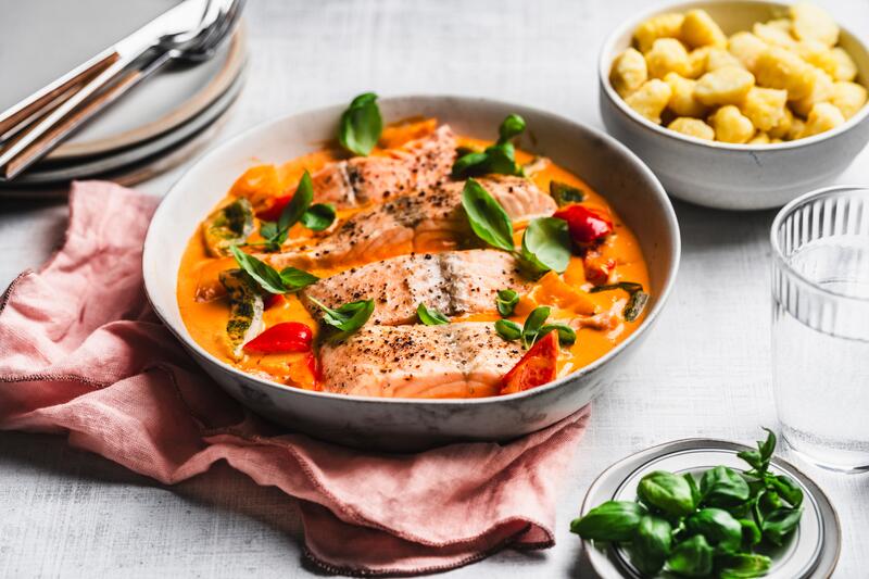 Lachs in Paprika-Rahmsoße in tiefem Teller mit angestellten Gnocchi